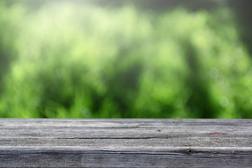 Fototapeta premium Soft blur wooden table and defocused green background.