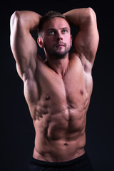 Fototapeta premium portrait of young handsome muscular man posing over grey