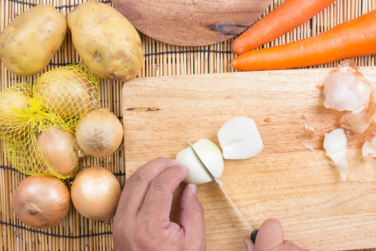 Chef cutting the onion on a wooden board