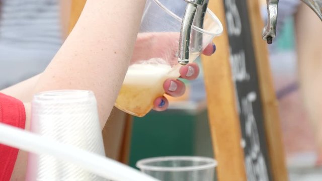  woman pours beer into a disposable cup
