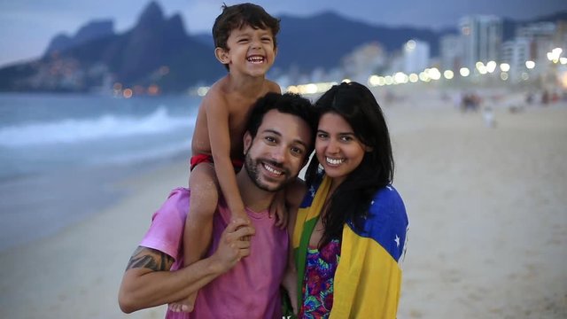 A young family stands on the beach at night and smiles into the camera