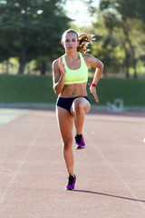 Fototapeta na wymiar Fit young woman running on track field.
