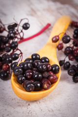 Heap of elderberry with wooden spoon on old wooden background, healthy food