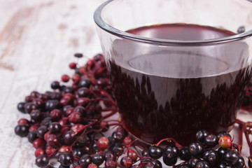 Bunch of fresh elderberry with juice on old wooden background, healthy nutrition