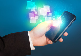 Hand holding smart phone with abstract glowing squares