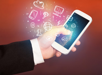 Hand holding smartphone with media icons