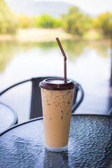 Iced coffee in plastic glass on modern table. Selective focus.