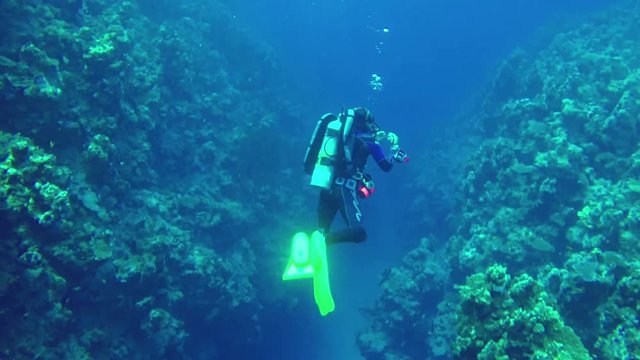 Underwater scene Diver shows signs diving between two rocks of corals in Red Sea. Dahab. Egypt. Target camera. 4k video