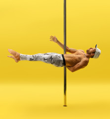 Photo of modern male dancer performing on pylon