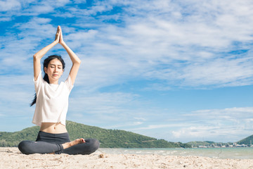 Fototapeta na wymiar young woman practicing yoga on the beach