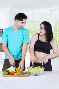 Couple preparing salad in kitchen