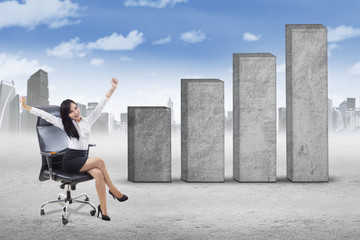 Successful woman on chair and business graph