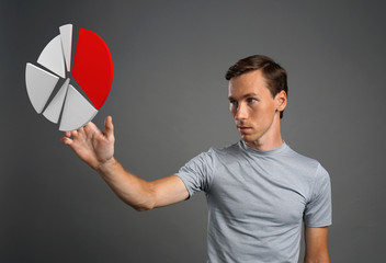 Man in t-shirt working with pie chart on grey background.