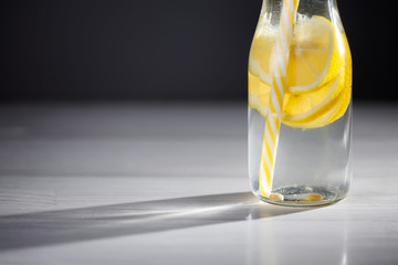 Yellow bottle of lemonade with lemons and straw.