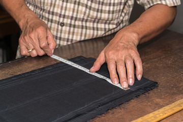 Tailor at work, drawing line on fabric with chalk
