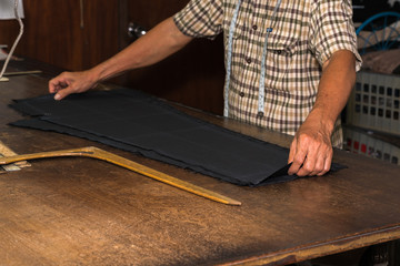 Tailor at work, drawing line on fabric with chalk
