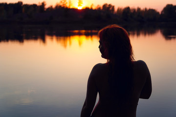 Fototapeta premium Silhouette of a woman in the river at sunset.