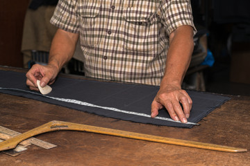 Tailor at work, drawing line on fabric with chalk
