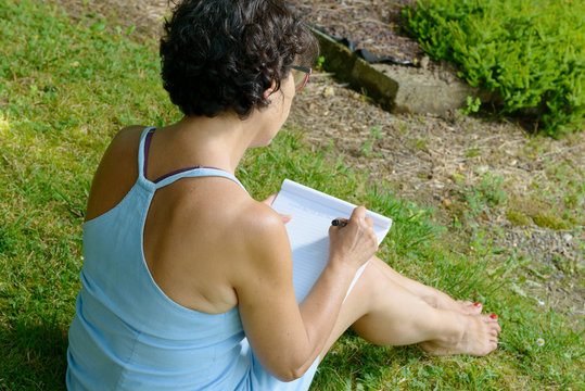 mature woman writes a letter in the garden