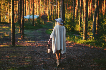 Obraz premium woman tourist with a lantern in a forest at sunset