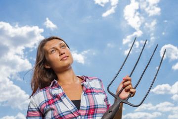 Happy female farmer with pitchfork in field