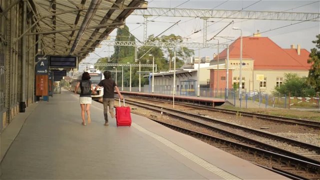 Running couple with a suitcase in a train station