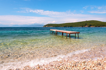 A small pier on Avlaki beach with crystal clear water. Corfu, Greece.