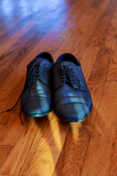 Shiny black men's shoes for the bride, lying on the floor