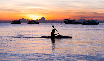 Silhouette of a man rowing in the canoe