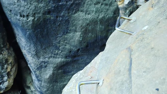Climbers ladder. Iron twisted rope fixed in block by screws snap hooks. The rope end anchored into sandstone rock. 