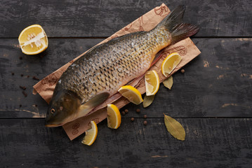 Carp fish and lemon on the table derevya...