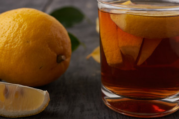 Tea with lemon and pieces of lemon on a wooden table close