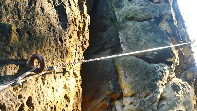 Climbers ladder. Iron twisted rope fixed in block by screws snap hooks. The rope end anchored into sandstone rock. 