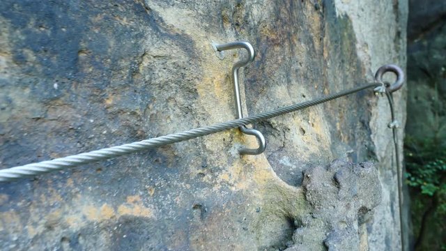 Climbers ladder. Iron twisted rope fixed in block by screws snap hooks. The rope end anchored into sandstone rock. 