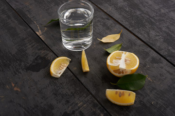 yellow lemons, leaves and glass of water on the table