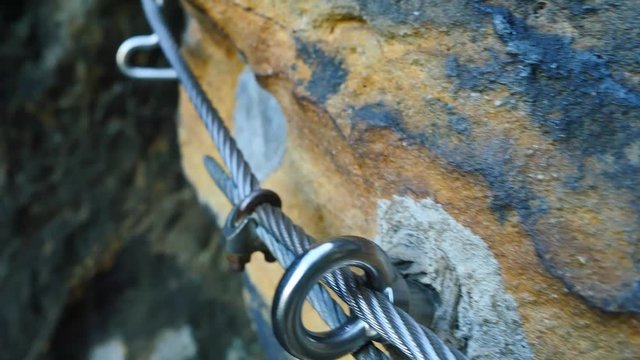 Climbers ladder. Iron twisted rope fixed in block by screws snap hooks. The rope end anchored into sandstone rock. 