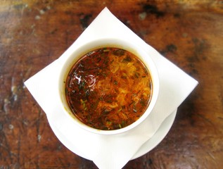 Bowl of vegetable soup with potatoes, carrots and parsley isolated on dark brown wooden background Top view