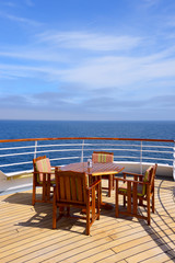 Fototapeta na wymiar Empty wooden deck chairs and table on ship