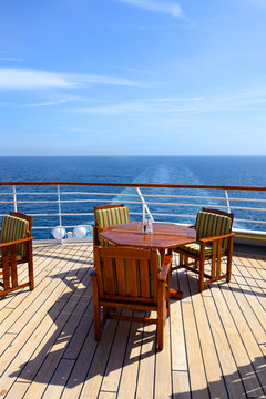 Empty wooden deck chairs and table on ship