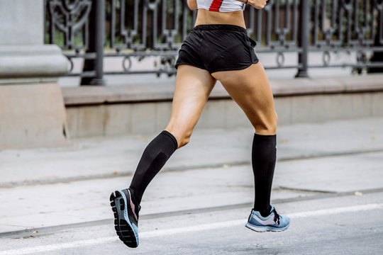 Side View Of Young Woman Legs In Compression Socks Athlete Running A Marathon