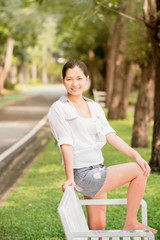 Young asian woman relaxing outdoors looking happy and smiling