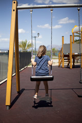 Young girl playing on swing in playground