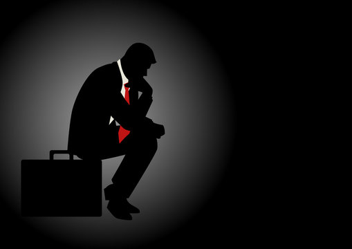 Pensive businessman sitting on his briefcase