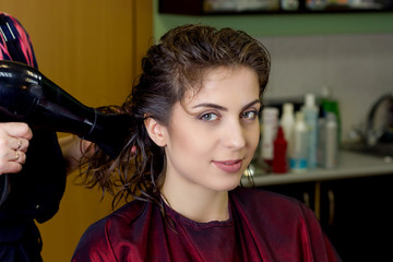 Young girl in hair dressing salon is drying her hair