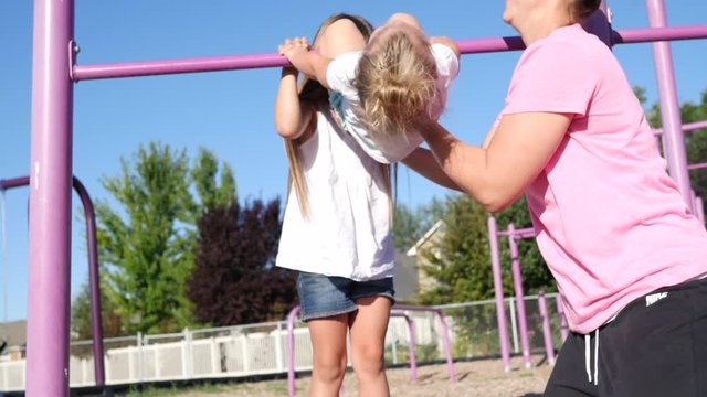 Mom and daughters play on jungle gym