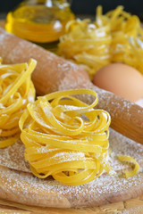 Ingredients for cooking pasta, raw pasta tagliatelle on a black