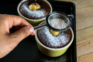 Girl powdered with sugar freshly baked desserts with pears, hands in the shot