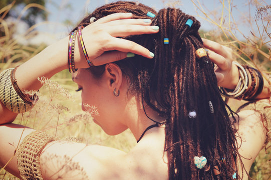 Beautiful young woman wearing dreadlocks hairstyle gathered in a ponytail and decorated assorted beads