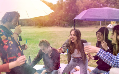 Young people having fun at picnic despite the rain at sunset