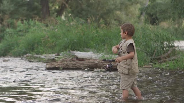 Slow motion of little boy fishing in creek